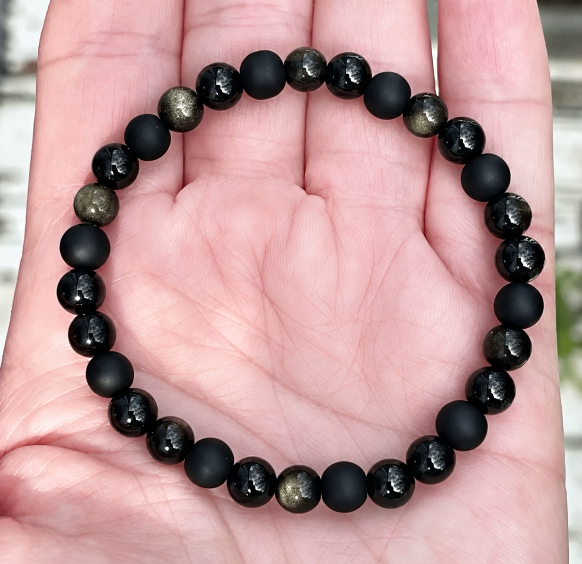 Round black bead bracelet combining matte, glossy and golden-sheen finishes