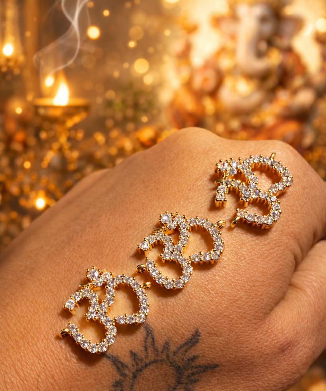 Three Om jewellery charms with clear-stone detailing and gold-tone settings